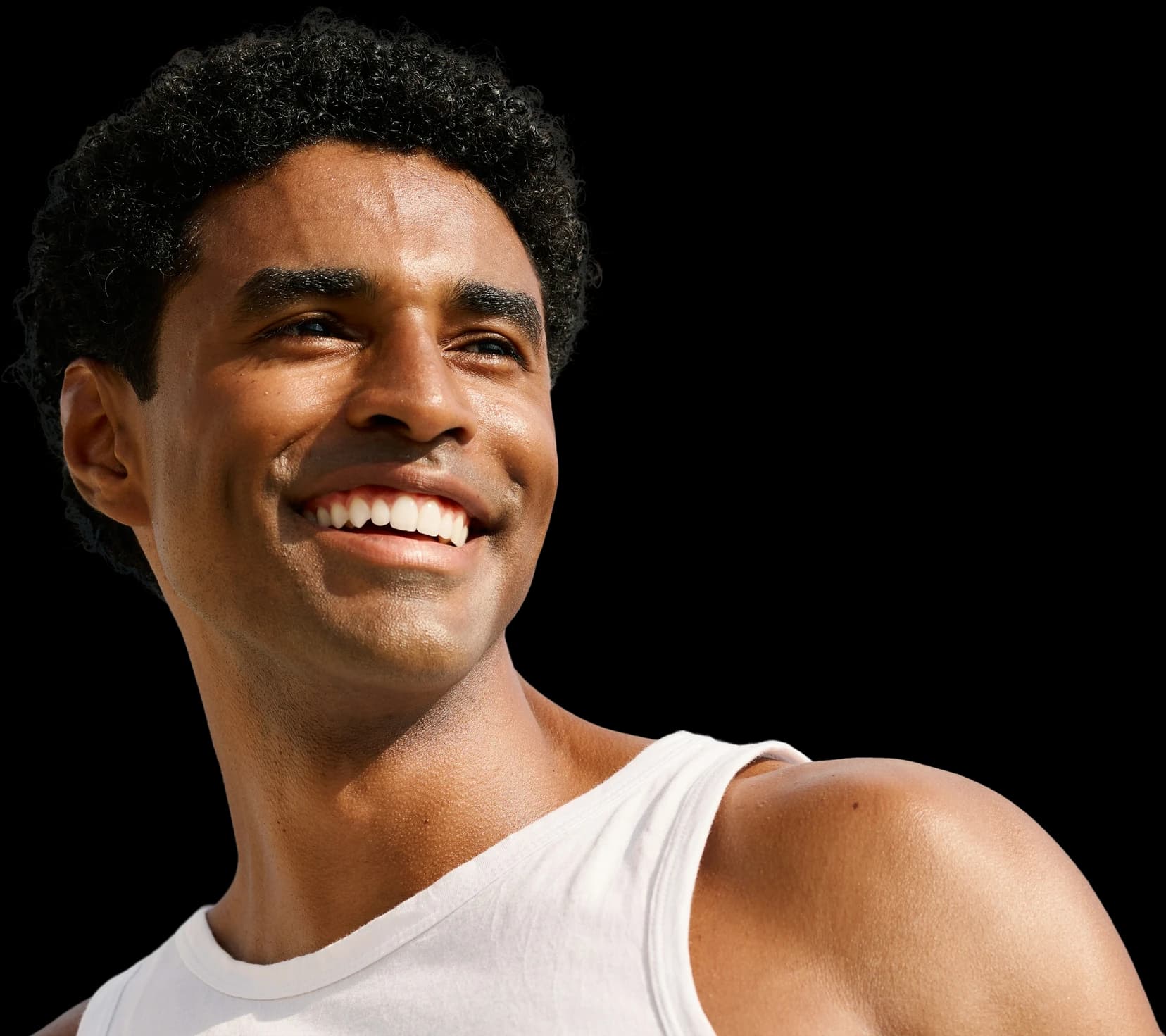 Smiling man in a white vest looking up into the sunlight